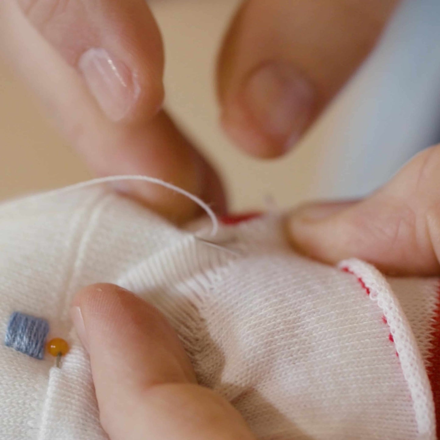 gros plan sur des mains qui cousent le visage d'un doudou singe chaussette