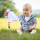 joli petit garçon joue dans l'herbe avec son doudou à rayures et longues et douces oreilles rouges et blanches 
